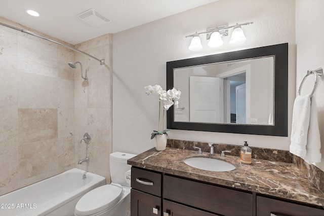 full bathroom featuring vanity, tiled shower / bath combo, and toilet