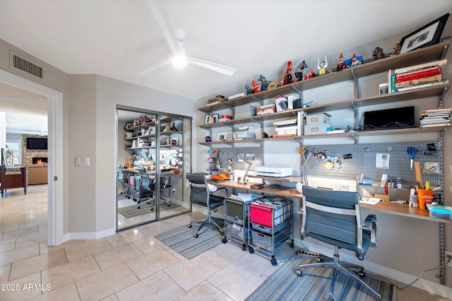 office space featuring ceiling fan, light tile patterned floors, and a fireplace