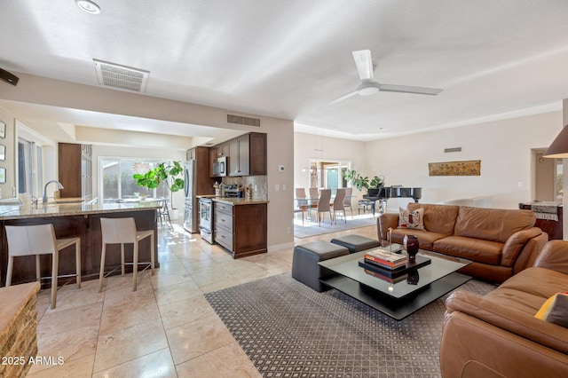 living room featuring ceiling fan, sink, and light tile patterned floors