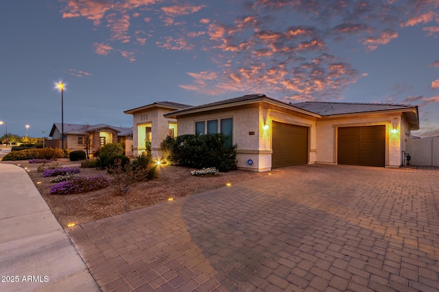 view of front of home featuring a garage, decorative driveway, fence, and stucco siding