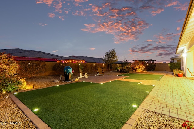 yard at dusk with a fenced backyard and a patio