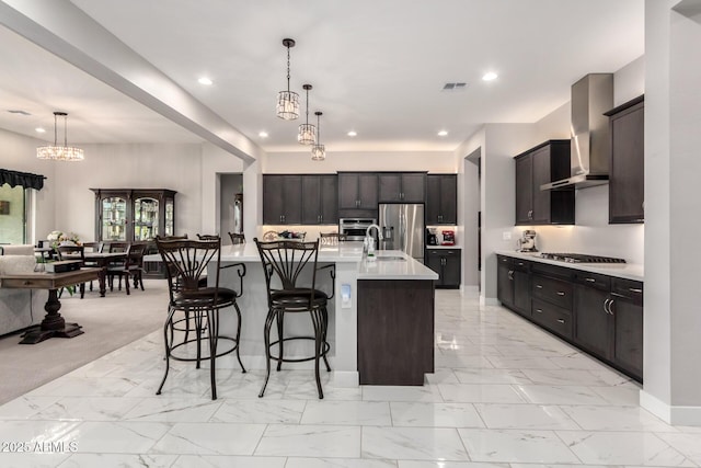 kitchen with recessed lighting, stainless steel appliances, marble finish floor, wall chimney range hood, and light countertops