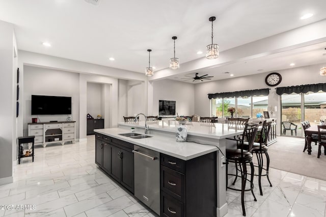 kitchen with a sink, dark cabinets, open floor plan, and dishwasher