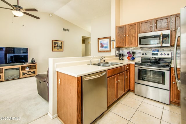 kitchen with lofted ceiling, stainless steel appliances, kitchen peninsula, and sink