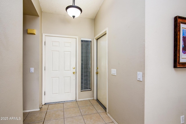 entryway with a textured ceiling and light tile patterned flooring