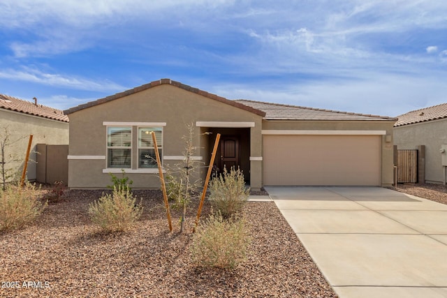 single story home with a garage, a tiled roof, concrete driveway, and stucco siding