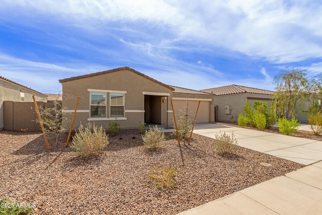 view of front of home with stucco siding, concrete driveway, an attached garage, fence, and a tiled roof