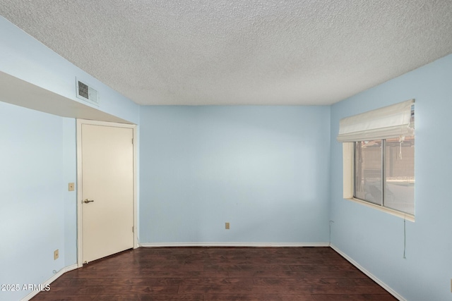 empty room featuring dark hardwood / wood-style flooring and a textured ceiling