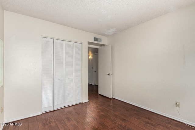 unfurnished bedroom with a closet, dark wood-type flooring, and a textured ceiling