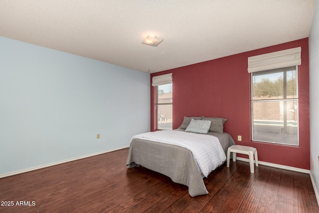 bedroom with multiple windows and dark hardwood / wood-style flooring