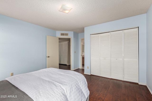 bedroom featuring dark hardwood / wood-style flooring, a textured ceiling, and a closet