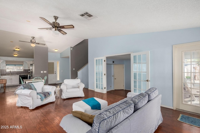 living room featuring a textured ceiling, french doors, dark hardwood / wood-style floors, and lofted ceiling