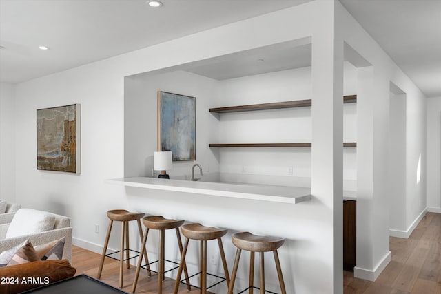 kitchen featuring a kitchen breakfast bar, kitchen peninsula, and hardwood / wood-style floors