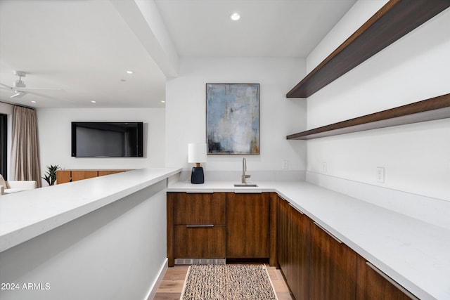 bar with ceiling fan, light wood-type flooring, and sink