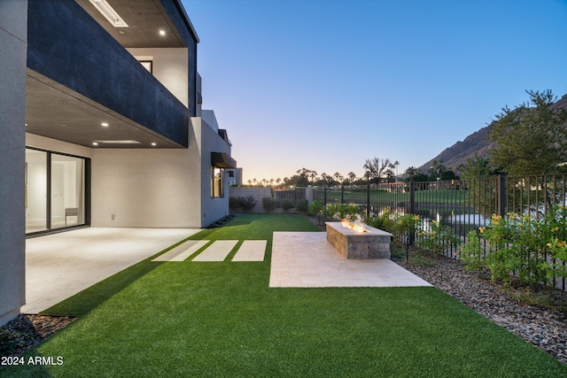 yard at dusk with a fire pit, a water view, and a patio