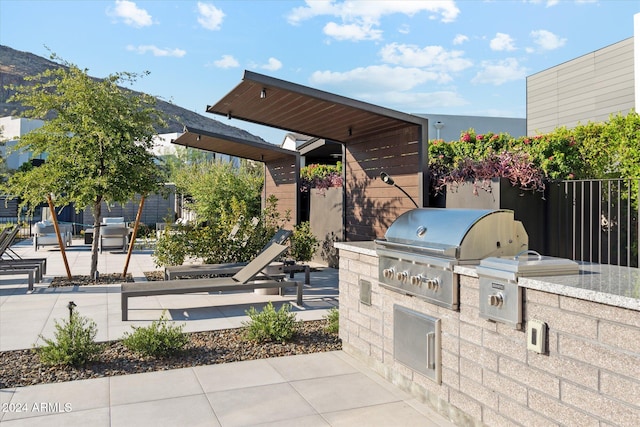 view of patio featuring a grill, a mountain view, and exterior kitchen