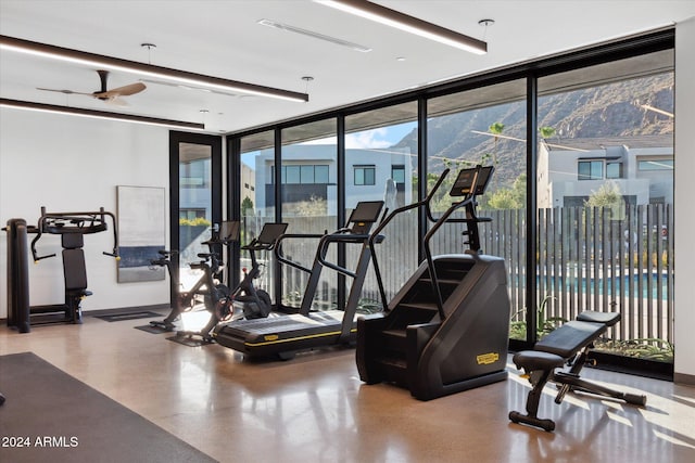 gym featuring concrete flooring, a wall of windows, plenty of natural light, and ceiling fan