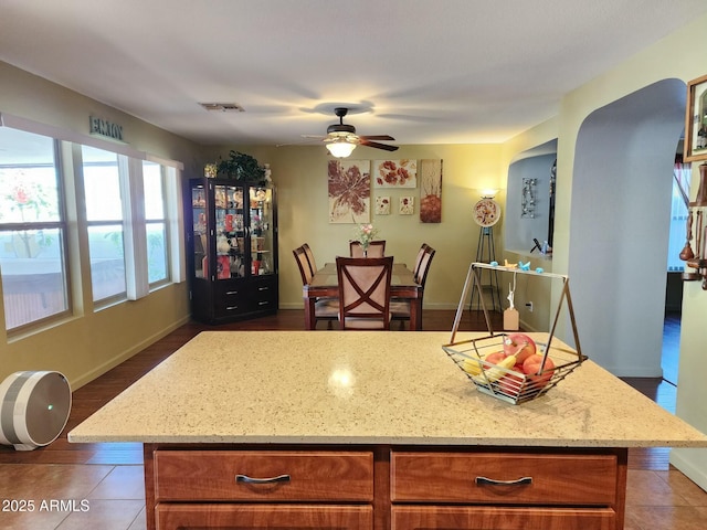 kitchen with light stone countertops, a center island, and ceiling fan