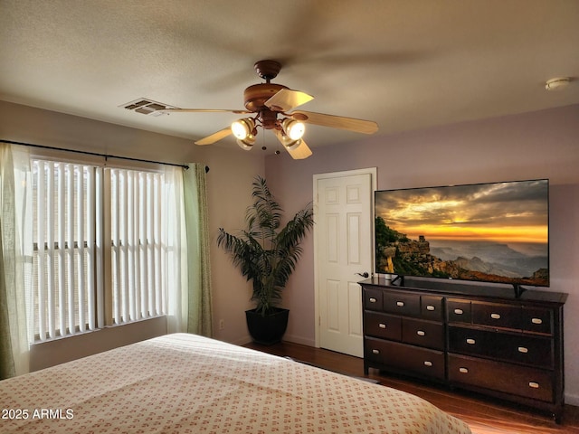 bedroom with dark hardwood / wood-style flooring, a textured ceiling, and ceiling fan