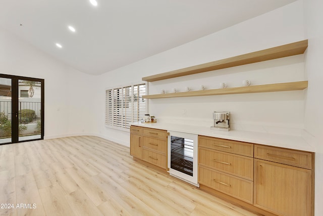 bar with light brown cabinets, light wood-type flooring, wine cooler, and vaulted ceiling