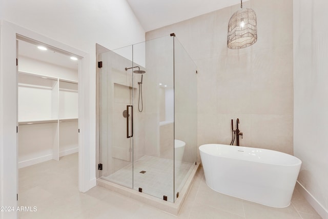 bathroom with tile patterned floors, tile walls, and shower with separate bathtub