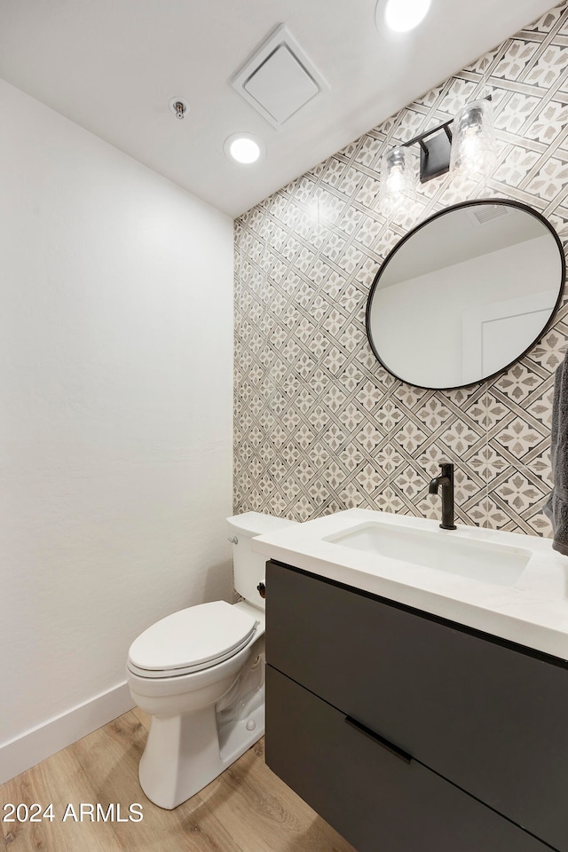 bathroom featuring hardwood / wood-style flooring, vanity, toilet, and backsplash