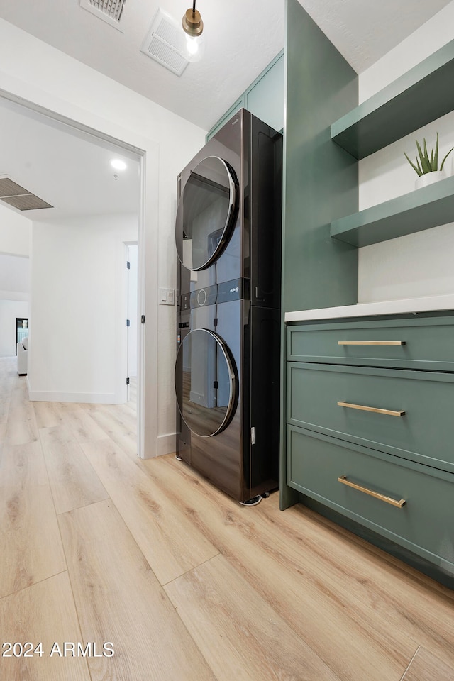 washroom with stacked washer and dryer and light hardwood / wood-style flooring