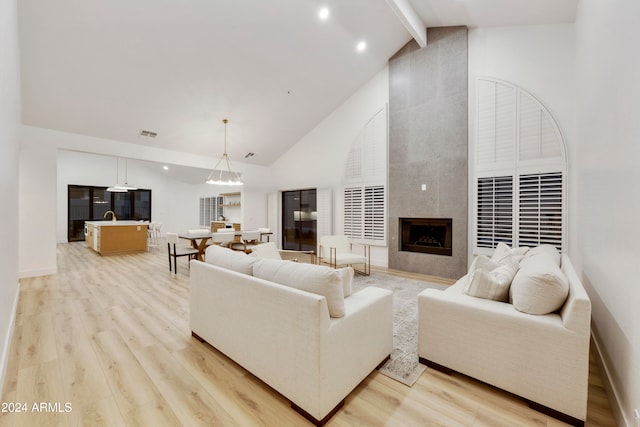 living room featuring beam ceiling, a premium fireplace, high vaulted ceiling, and light hardwood / wood-style floors