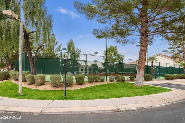 view of home's community with tennis court and a yard