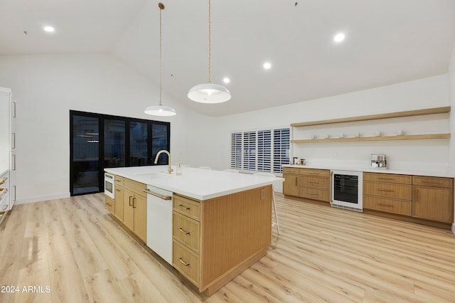 kitchen featuring light wood-type flooring, white dishwasher, a kitchen island with sink, sink, and wine cooler