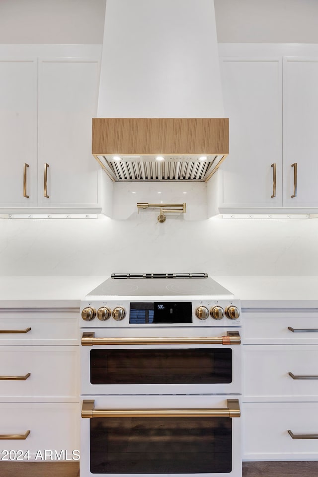 kitchen featuring premium range hood, white cabinets, and high end stainless steel range oven