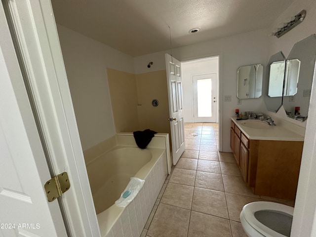 bathroom with tile flooring, large vanity, a textured ceiling, a relaxing tiled bath, and toilet