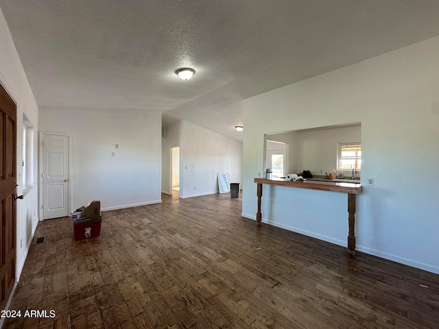 unfurnished living room featuring dark hardwood / wood-style floors, lofted ceiling, and a textured ceiling