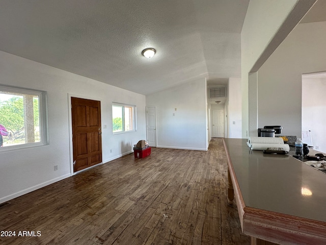 foyer featuring a textured ceiling, vaulted ceiling, and dark wood-type flooring