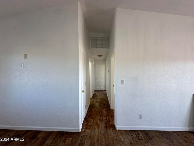 hall with vaulted ceiling and dark wood-type flooring