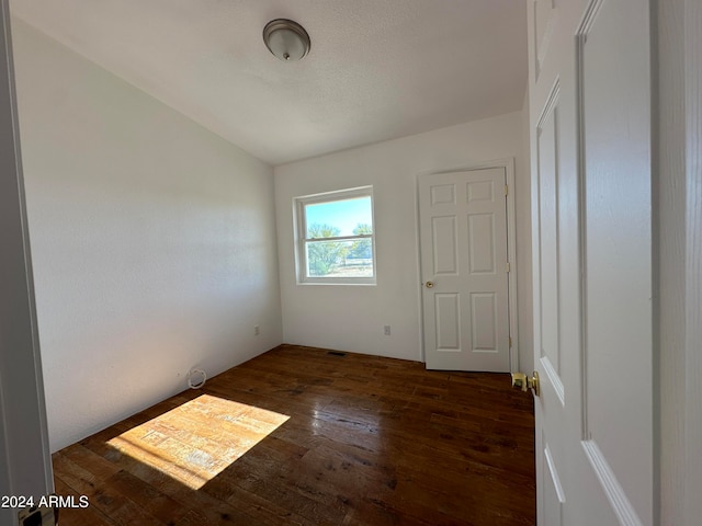 unfurnished room featuring dark hardwood / wood-style floors and lofted ceiling