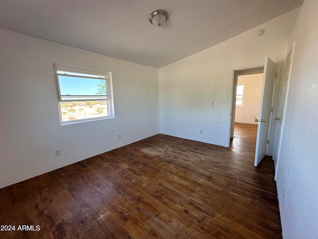 unfurnished room featuring dark hardwood / wood-style flooring and lofted ceiling
