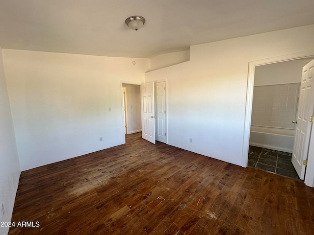 unfurnished bedroom with dark hardwood / wood-style flooring, vaulted ceiling, a closet, and ensuite bathroom