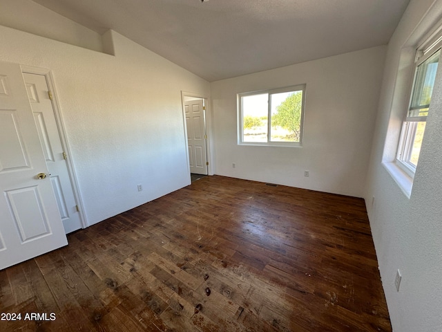 unfurnished bedroom with dark hardwood / wood-style flooring, multiple windows, and vaulted ceiling