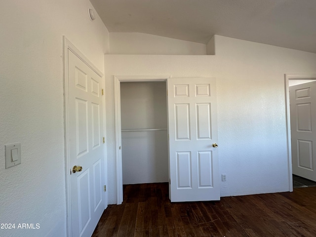 unfurnished bedroom featuring dark hardwood / wood-style flooring, a closet, and vaulted ceiling
