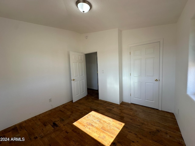 unfurnished bedroom with a closet and dark hardwood / wood-style floors