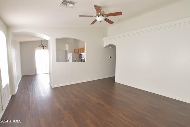 spare room with dark wood-type flooring, ceiling fan with notable chandelier, and lofted ceiling