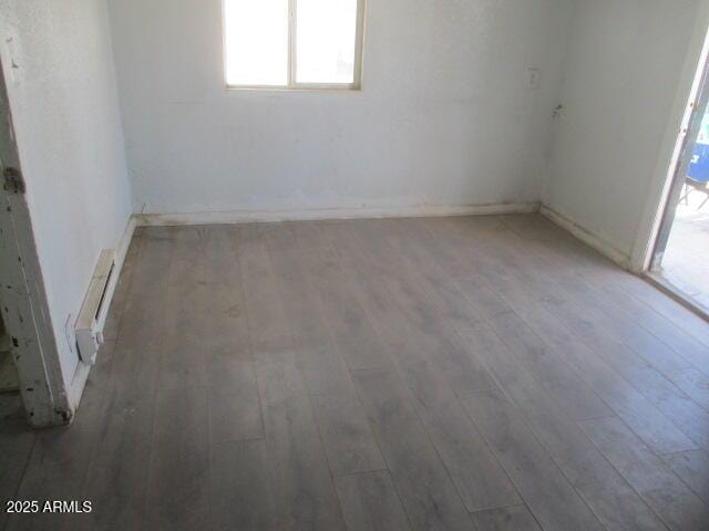 spare room with a baseboard heating unit and wood finished floors