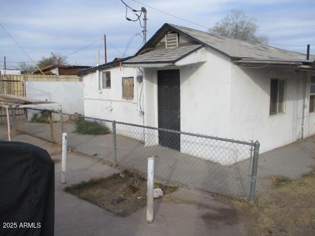 view of property exterior featuring a shingled roof, fence, and stucco siding