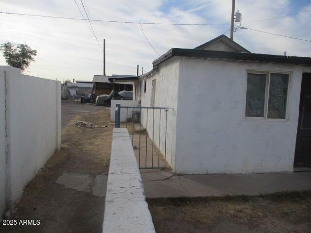 view of side of home featuring fence and stucco siding