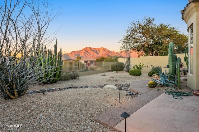 yard at dusk with a patio area and a mountain view