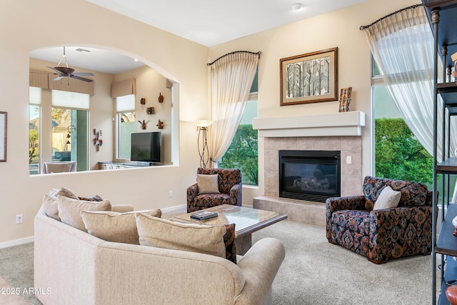 carpeted living room featuring a tile fireplace and ceiling fan