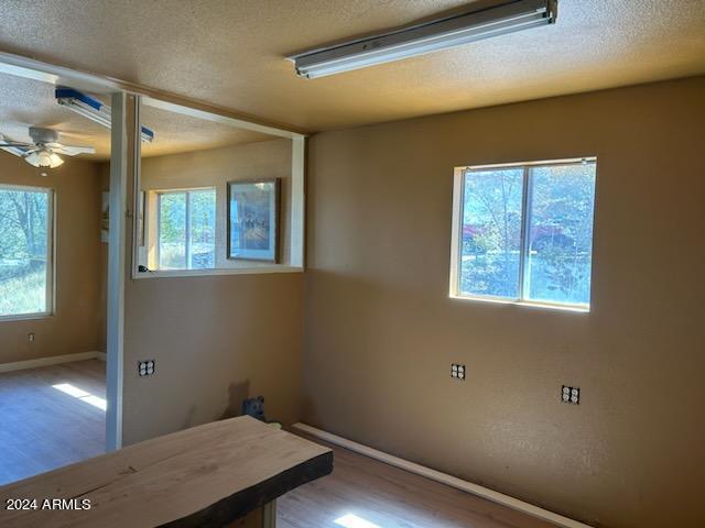 unfurnished room featuring ceiling fan, a textured ceiling, and wood-type flooring