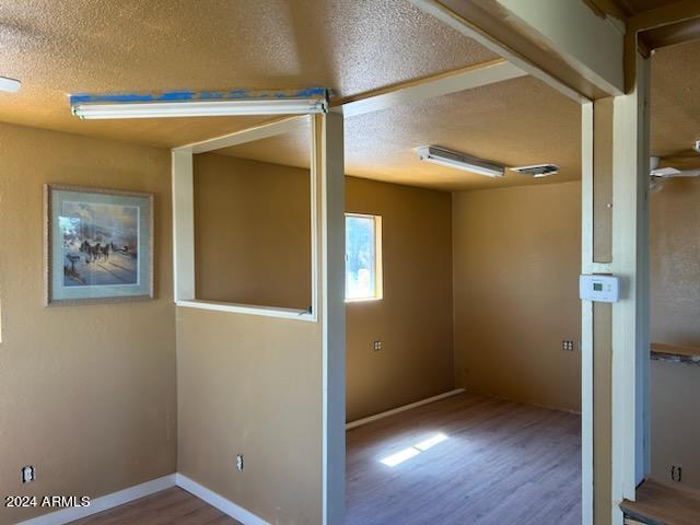 unfurnished room with hardwood / wood-style flooring and a textured ceiling