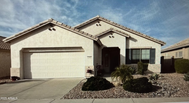 view of front of house with a tile roof, a garage, driveway, and stucco siding